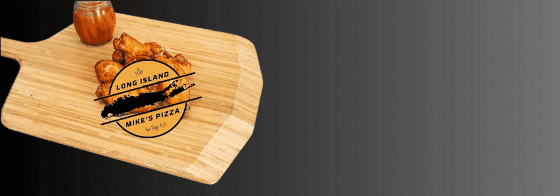 Cutting board with chicken wings, sauce, and a "Long Island Mike's Pizza" logo.